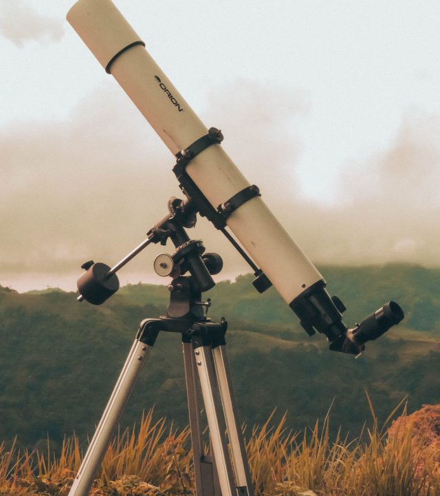 A telescope on a tripod set against a lush mountain backdrop under cloudy skies in Cebu.